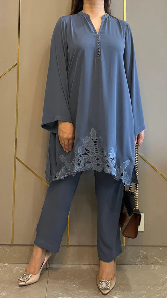 Woman wearing a blue outfit with lace details against a neutral background